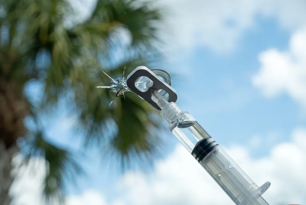 Resin injector repairing a star-shaped windshield chip
