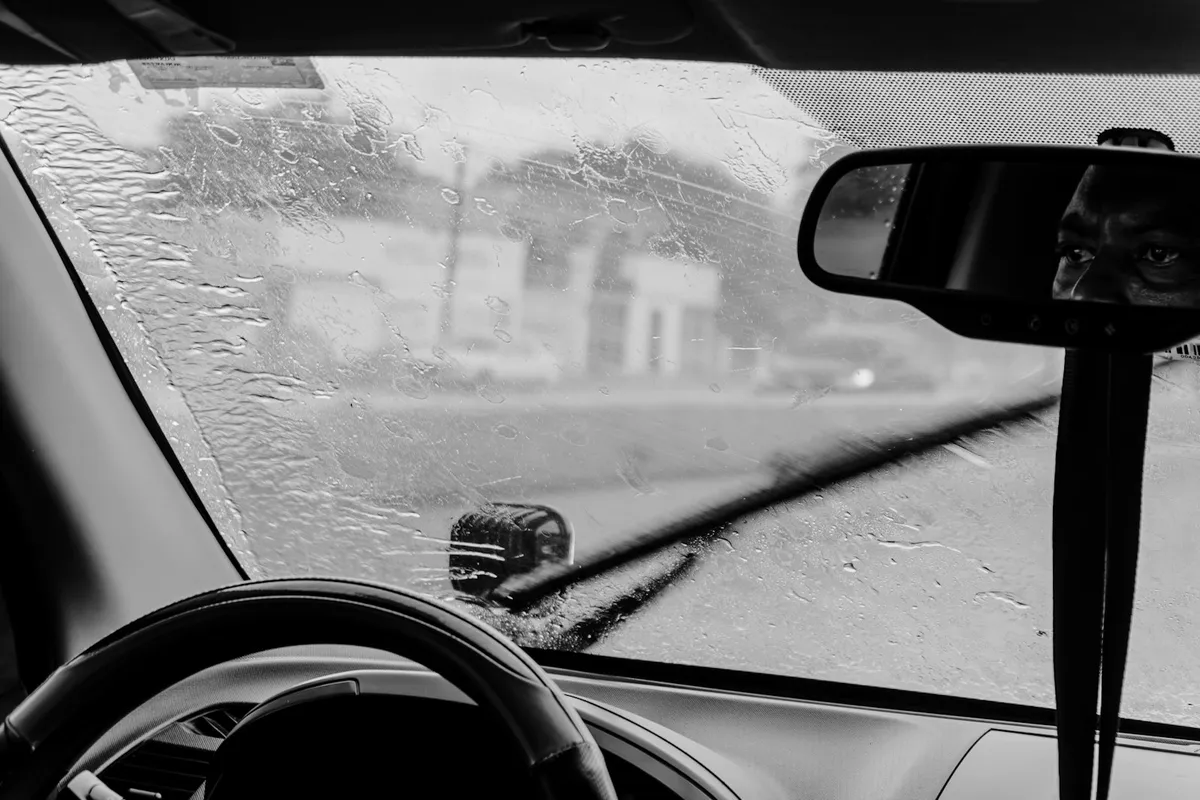 Driver view through a windshield as wipers clear heavy rain